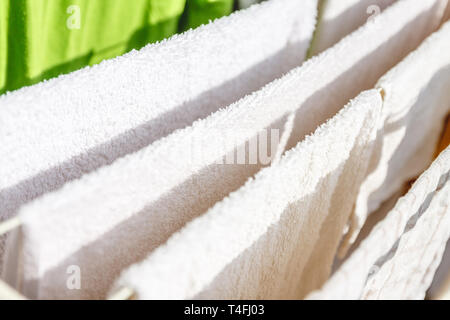 Weiße und farbige Bettwäsche und Handtücher auf der Wäscheleine getrocknet werden. Stockfoto