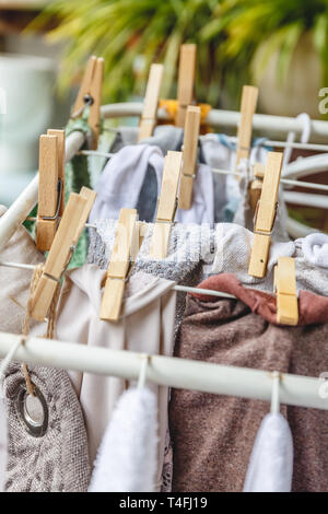 Weiße und farbige Bettwäsche auf die Wäscheleine mit Wäscheklammern aus Holz zu trocknen. Stockfoto