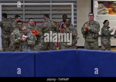 Miniatur Krieger von Familien über 2Nd Brigade Combat Team, 10 Mountain Division, versammelten Soldaten der 41. Engineer Battalion während der Commando Brigade des zweiten 'Nerf Kriege' Match in einem behelfsmäßigen Schlachtfeld statt der gesamten Elze Sports Complex Basketballplatz konfiguriert, 10. April 2019, am Fort Drum, New York. Schaum Dart die Turnhalle während der ÜBERSÄT 'Nur zum Spaß' Ereignis als gegensätzliche Kräfte von Popcorn und Zuckerwatte in einem Spiel Feuergefecht engagiert vorangetrieben. Stockfoto