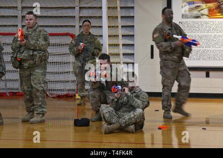 Miniatur Krieger von Familien über 2Nd Brigade Combat Team, 10 Mountain Division, versammelten Soldaten der 41. Engineer Battalion während der Commando Brigade des zweiten 'Nerf Kriege' Match in einem behelfsmäßigen Schlachtfeld statt der gesamten Elze Sports Complex Basketballplatz konfiguriert, 10. April 2019, am Fort Drum, New York. Schaum Dart die Turnhalle während der ÜBERSÄT 'Nur zum Spaß' Ereignis als gegensätzliche Kräfte von Popcorn und Zuckerwatte in einem Spiel Feuergefecht engagiert vorangetrieben. Stockfoto