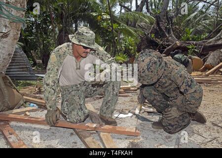 POLLAP, Föderierte Staaten von Mikronesien (11. April 2019) US-Marine Master-at-Arms 1. Klasse Justin Peterson, links, hält ein Stück Holz für Dach zu reparieren, während US Marine Corps Lance Cpl. Jessie Mercado Schnitte mit einer Hand sah während der Pacific Partnerschaft 2019. Pazifische Partnerschaft, der nun in seinem 14. Iteration, ist die größte jährliche internationale humanitäre Hilfe und Katastrophenhilfe Abwehrbereitschaft Mission im Indopazifik durchgeführt. Jedes Jahr, die Mission Team arbeitet gemeinsam mit Gastgeber und Partner Nationen regionaler Interoperabilität und Disaster Response Funktionen, erhöhen die Stabi zu verbessern Stockfoto