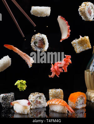 Verschiedene Sushi in Bewegung auf einem schwarzen Hintergrund erfasst Stockfoto