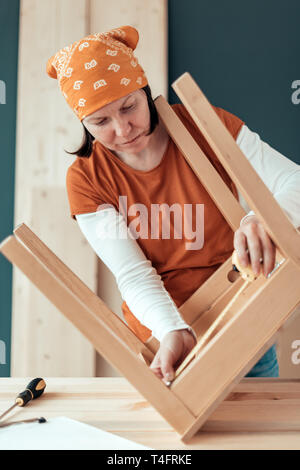 Frau Carpenter Reparatur Holz Stuhl Sitz in Small Business Holzarbeiten workshop Stockfoto