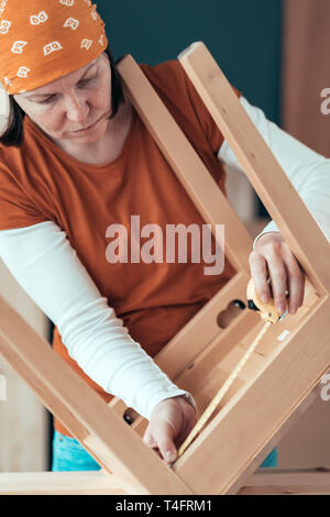 Frau Carpenter Maßband Holz Stuhl Sitz in Small Business Holzarbeiten Workshop, bis der Hände schließen, selektiven Fokus Stockfoto