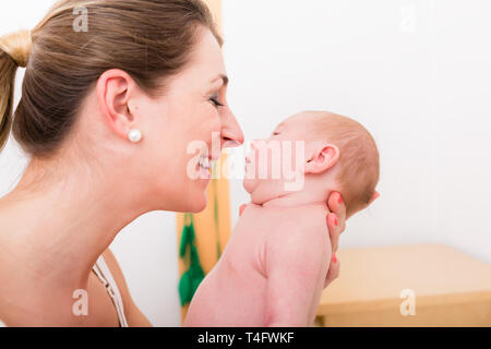 Lächelnde Mutter liebevoll ihr neugeborenes Baby Stockfoto