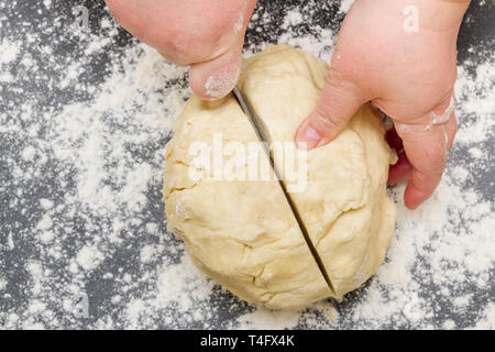 Schneiden ein großes Stück Teig auf einer mit Mehl für die Herstellung von Quark cookies Stockfoto