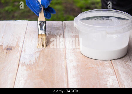 Mann malt eine weiße Lackoberfläche. Färbung Boards. Malerei Holzbretter. Stockfoto