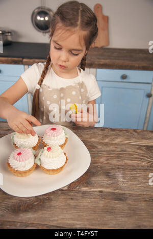 Kind Tochter in der Küche dekorieren Kuchen Sie ist mit ihrer Mutter gemacht. little Helper, hausgemachte Speisen. Kuchen im Vordergrund. Stockfoto