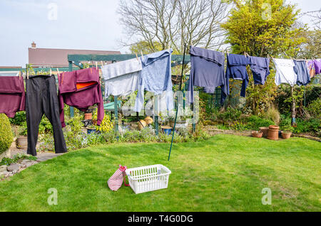 Kleidung hängen heraus auf eine Wäscheleine in einem Wohngebiet zurück Garten im Frühling zu trocknen. Stockfoto