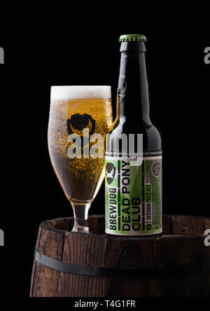 LONDON, UK, 06. Juni, 2018: Flasche und Glas von Toten Pony Club Pale Ale, Bier aus der Brauerei Brewdog auf alten Holzfass auf schwarzem Hintergrund. Stockfoto