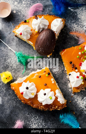 Hohen winkel Blick auf einige Stücke von Mona de Pascua, ein Kuchen in Spanien am Ostermontag gegessen, mit einem Schokoladen-ei, einem flauschigen Küken und Federn o Stockfoto