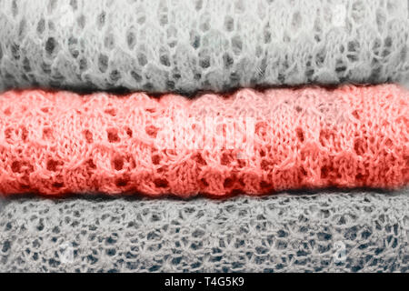 Stilvolle gestrickt, pastellfarbenen Pullover und eins in der Farbe des Jahres 2019 in verschiedenen Strickmuster im Stapel gefaltet. Close Up, kopieren. Stockfoto