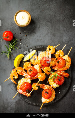 Gegrillte Meeresfrüchte. Köstliche gegrillte Tiger Garnelen mit Tomaten, Zitrone und Soße auf einer Schiefer Board serviert. Fisch und Meeresfrüchte. Ansicht von oben flach Hintergrund. Stockfoto