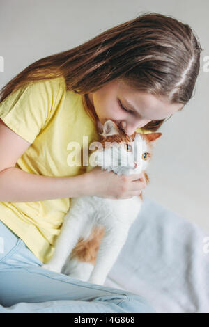 Cute tween Girl in gelben T-Shirt mit ihrer weißen Katze zu Hause Stockfoto