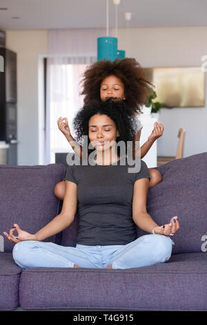 Afrikanische amerikanische Frau mit der kleinen Tochter Üben Yoga zu Hause Stockfoto