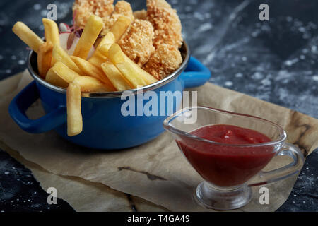 Mittagessen oder einen Snack - Fried Chicken Streifen und Pommes frites in eine Metallwanne mit Tomatensoße. Handwerk Papier im Hintergrund. Stockfoto