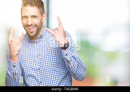 Jungen gutaussehenden Mann über isolierte Hintergrund schreien mit verrückten Ausdruck tun Rock Symbol mit hands up. Musik Star. Schwere Konzept. Stockfoto