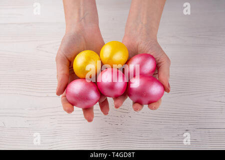 Hände halten moderne bemalte Ostereier. Selektive konzentrieren. Weiß Holz- Hintergrund Stockfoto