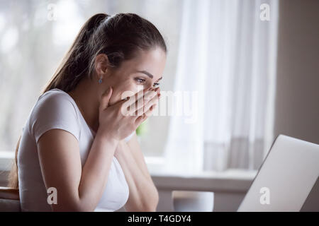 Aufgeregt Frau unerwartet guten Nachricht auf dem Computer zu Hause. Stockfoto