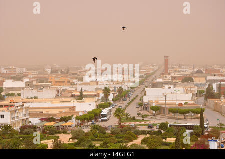 Sandsturm erstreckt sich auf den Straßen der Stadt El Djem (El Jem) in Tunesien, in Nordafrika. Ansicht von oben, mit zwei Tauben fliegen gegen eine staubige Himmel. Stockfoto