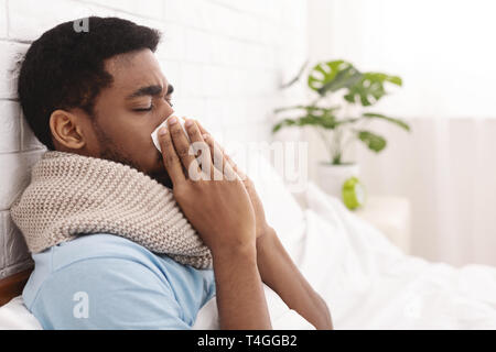 Junge kranke Mann im Bett Reinigung rotzig Nase Stockfoto