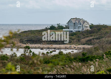 Kleines Haus unter Büschen und Gras mit Blick auf den felsigen Strand, Block Island, Rhode Island Stockfoto