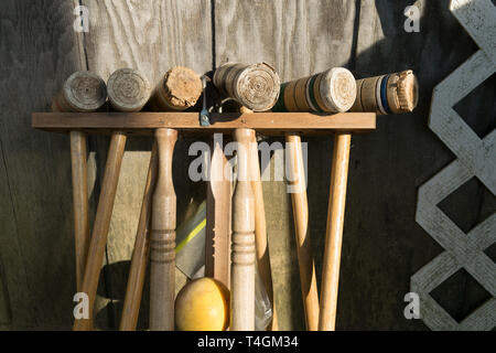 Alte gut genutzt Croquet Mallets in einem Rack, lehnte sich gegen eine Holzwand, mittellange Aufnahme Stockfoto