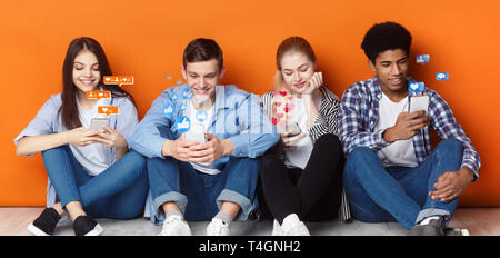 Blogger mit Telefonen Chatten in sozialen Netzwerken, orange Wand Stockfoto