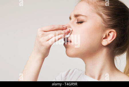 Hoher Blutdruck. Junge Frau leiden, Nasenbluten, Blut und Gewebe, freier Speicherplatz Stockfoto