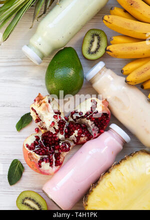 Smoothies oder Milchshakes in verschiedenen Farben, die in Gläsern mit bunten Früchten auf weißem Holz- Hintergrund, Ansicht von oben. Von oben. Flach. Kopieren Sie sp Stockfoto