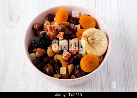 Trockenfrüchte und Nüsse in einem rosa Schüssel über weiße Holz- Oberfläche, Low Angle View. Stockfoto