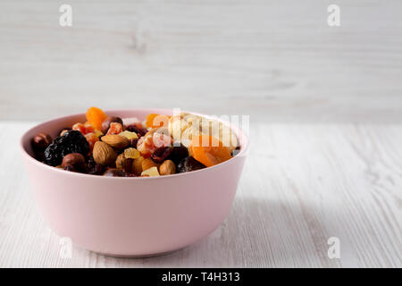 Trockenfrüchte und Nüsse in einem rosa Schüssel über weiße Holz- Hintergrund, Seitenansicht. Kopieren Sie Platz. Stockfoto