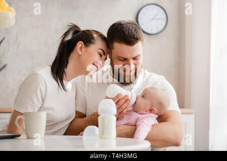 Glückliches junges paar Fütterung Säugling von der Flasche Stockfoto