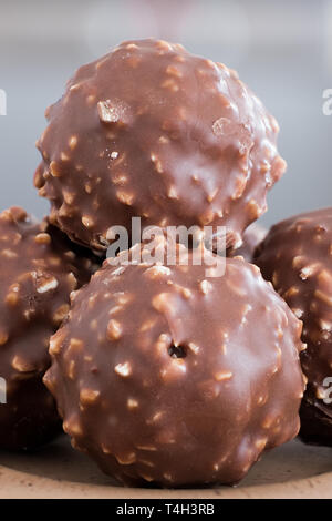 Vier runde Schokolade und zerkleinerte Mandeln knusprige Kugeln auf einem kleinen Servierteller mit einem weichen verschwommenen Hintergrund. Ein gutes Bild für ein Feinkostgeschäft, Süße R Stockfoto