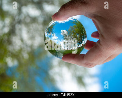 Eine nicht erkennbare Person mit einem Kristall Kugel in seiner Hand mit einer Landschaft Reflexion Stockfoto