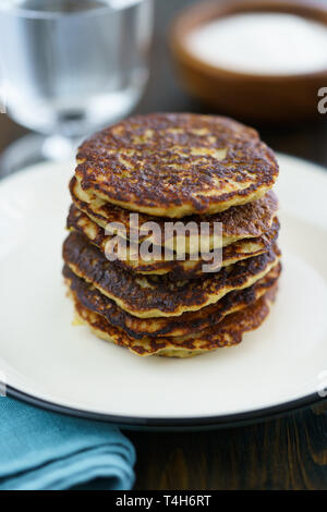 Kartoffelpuffer draniki serviert auf einem weißen Teller. Dunkler Holztisch, Blau Leinen Servietten, hohe Auflösung Stockfoto