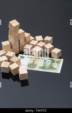 Chinesischer 1 Yuan-Schein und verstreute Holzsteine. Zusammenbruch des chinesischen Renminbi, Einbruch des chinesischen Aktienmarkts, Zusammenbruch des chinesischen Bankensektors, chinesische Schuldenkrise. Stockfoto