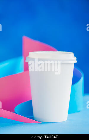 Leeres Papier Becher für Kaffee auf einer abstrakten Hintergrund mit modernen Papier Skulptur. Papier Pyramiden und Kurven Design in Pastellfarben. Stockfoto