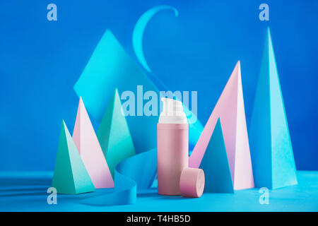 Kosmetik und Hautpflege Design mit rosa Rohre und moderne Papier Skulptur in Pastelltönen auf einem blauen Hintergrund mit kopieren. Modernes Produkt Hg Stockfoto