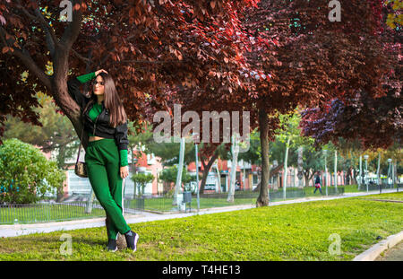 Murcia, Spanien, 15. April 2019: attraktive junge Frau steht von einem Vogel Kirschbaum im City Park suchen und Flirten, verführen mit Kamera im Herbst Saison. Stockfoto