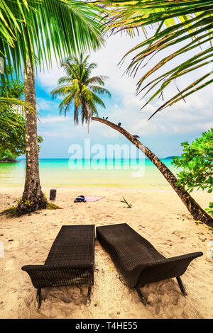 Natur Landschaft tropischer Strand mit Landschaft Chaiselongue für ein paar Touristen auf Hintergrund kristallklare Meer Wasser und Palmen Stockfoto