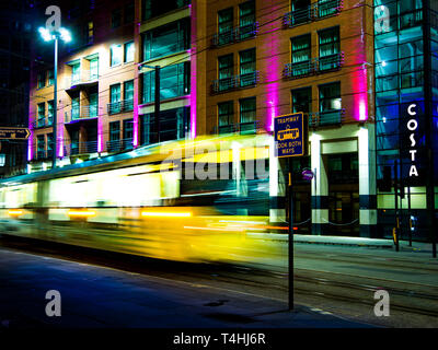 Bunte, Neon, Bewegungsunschärfe, gelben Straßenbahn, night street scene, Manchester, UK Stockfoto