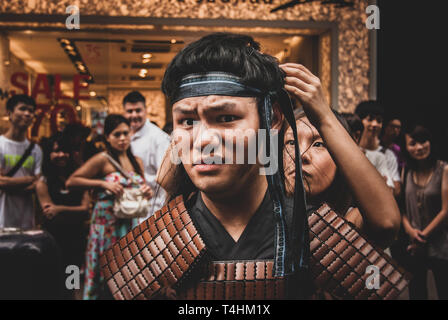 Nicht identifizierte Street Performer. Asiatischer Mann, das Tragen der traditionellen chinesischen Krieger Rüstung, die Vorbereitung für die Parade. Street Photography. Chinesischen Lebensstil Stockfoto