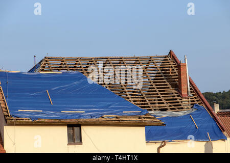 Die plane deckt das Dach des alten Hauses in der Rekonstruktion. Die schützende Plane auf dem Dach ist unvollständig. Stockfoto