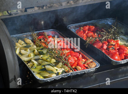 16 April 2019, Brandenburg, Fürstenwalde: klein geschnittenes Gemüse wie Zucchini, Tomaten und Paprika sind in Aluminium Fächer auf einem Grill platziert. Foto: Patrick Pleul/dpa-Zentralbild/ZB Stockfoto