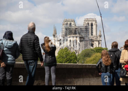 Paris, Frankreich. 17. Apr 2019. Ein Kran steht neben der Pariser Kathedrale Notre-Dame, von den Besuchern der Stadt angesehen wird. Das Feuer am Montag (15.04.2019) hatte die Kathedrale - ein wichtiges Wahrzeichen der französischen Hauptstadt und ein touristischer Magnet für Millionen von Menschen jedes Jahr besucht zerstört. Zur gleichen Zeit, das Feuer löste eine Welle der Hilfsbereitschaft. Foto: Marcel Kusch/dpa Quelle: dpa Picture alliance/Alamy leben Nachrichten Stockfoto