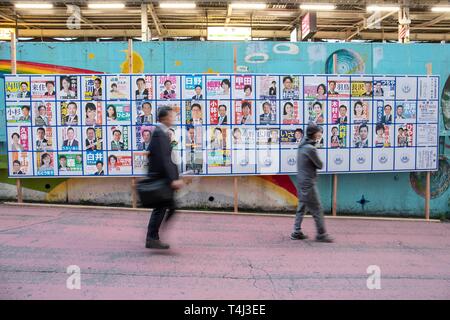 Tokio, Japan. 17 Apr, 2019. Fußgänger vorbei an eine Plakatwand mit Postern Kandidaten für Unified lokale Umfragen für April 21 errichtet, außerhalb Nakano Station. Renho, Mitglied des konstitutionellen Demokratischen Partei Japans (CDP) zeigten die Unterstützung für die Partei anderen Kandidaten vor der Unified Kommunalwahlen, die am 21. April stattfinden wird. Credit: Rodrigo Reyes Marin/LBA/Alamy leben Nachrichten Stockfoto