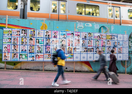 Tokio, Japan. 17 Apr, 2019. Fußgänger vorbei an eine Plakatwand mit Postern Kandidaten für Unified lokale Umfragen für April 21 errichtet, außerhalb Nakano Station. Renho, Mitglied des konstitutionellen Demokratischen Partei Japans (CDP) zeigten die Unterstützung für die Partei anderen Kandidaten vor der Unified Kommunalwahlen, die am 21. April stattfinden wird. Credit: Rodrigo Reyes Marin/LBA/Alamy leben Nachrichten Stockfoto