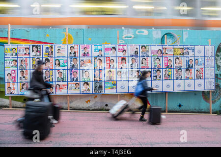 Tokio, Japan. 17 Apr, 2019. Fußgänger vorbei an eine Plakatwand mit Postern Kandidaten für Unified lokale Umfragen für April 21 errichtet, außerhalb Nakano Station. Renho, Mitglied des konstitutionellen Demokratischen Partei Japans (CDP) zeigten die Unterstützung für die Partei anderen Kandidaten vor der Unified Kommunalwahlen, die am 21. April stattfinden wird. Credit: Rodrigo Reyes Marin/LBA/Alamy leben Nachrichten Stockfoto