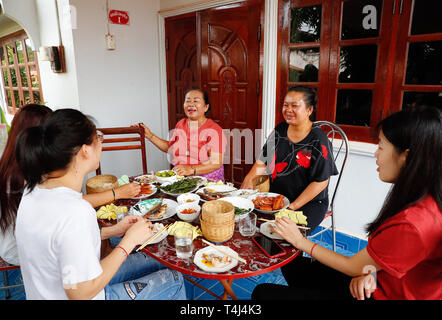 Vientiane, Laos. 24 Mär, 2019. Chinesische freiwillige Lehrkräfte Lin Jieyu (1. R) und Yao Changhua (1. L) Frühstück mit Schulleiterin des Verbots Nongping Volksschule Bounmy (3. R) und ihrer Familie in Vientiane, Laos, 24. März 2019 haben. Verbot Nongping Grundschule wurde im Jahr 2013 mit Hilfe von China gegründet. Credit: Wang Jingqiang/Xinhua/Alamy leben Nachrichten Stockfoto